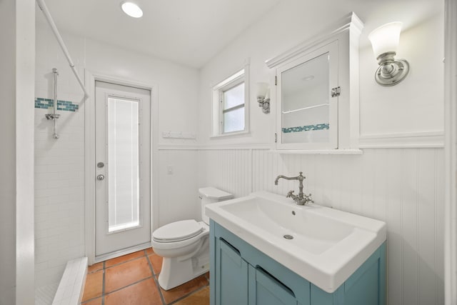 bathroom featuring vanity, toilet, and a tile shower