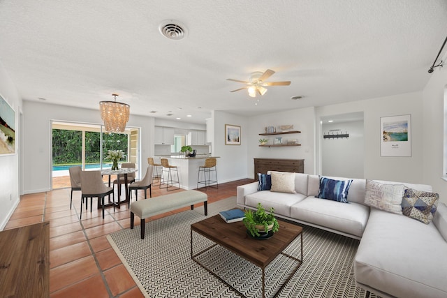 living room featuring tile patterned floors, ceiling fan with notable chandelier, and a textured ceiling