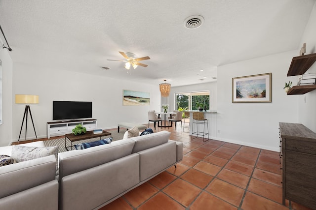 living room with a textured ceiling, dark tile patterned flooring, and ceiling fan