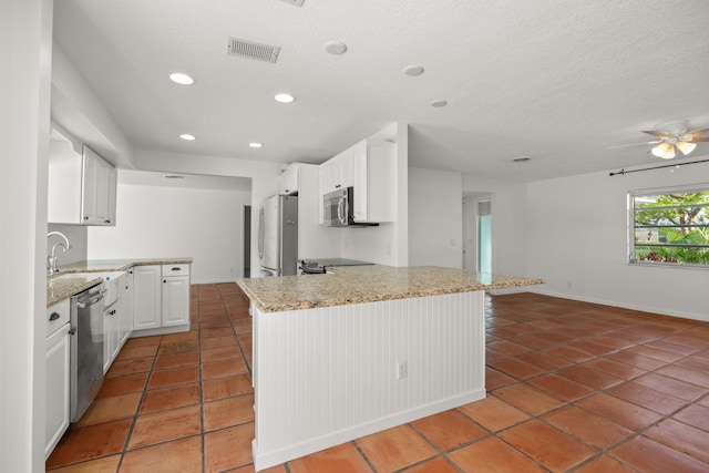 kitchen featuring appliances with stainless steel finishes, dark tile patterned floors, ceiling fan, sink, and white cabinetry