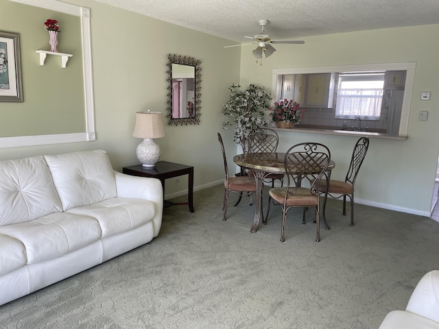 dining space with sink, ceiling fan, a textured ceiling, and carpet