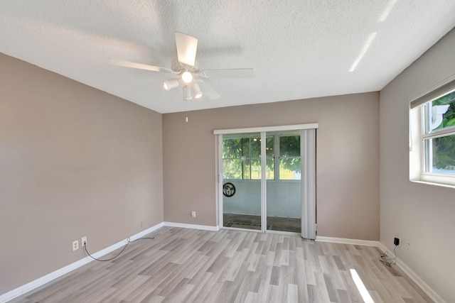 spare room with a healthy amount of sunlight, a textured ceiling, and light hardwood / wood-style flooring