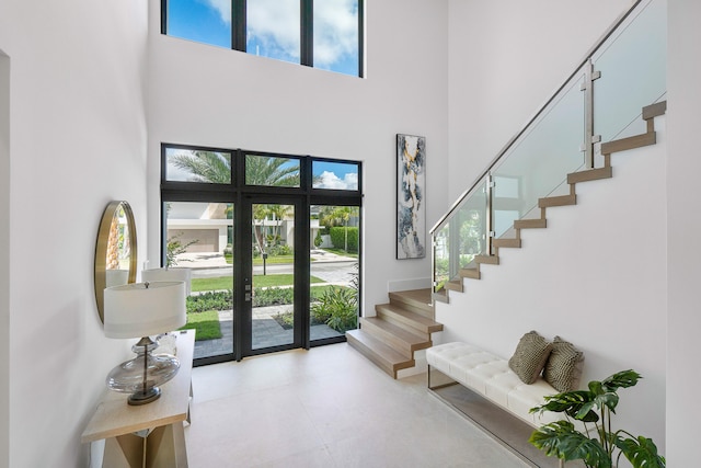 tiled foyer entrance featuring a towering ceiling, french doors, and plenty of natural light