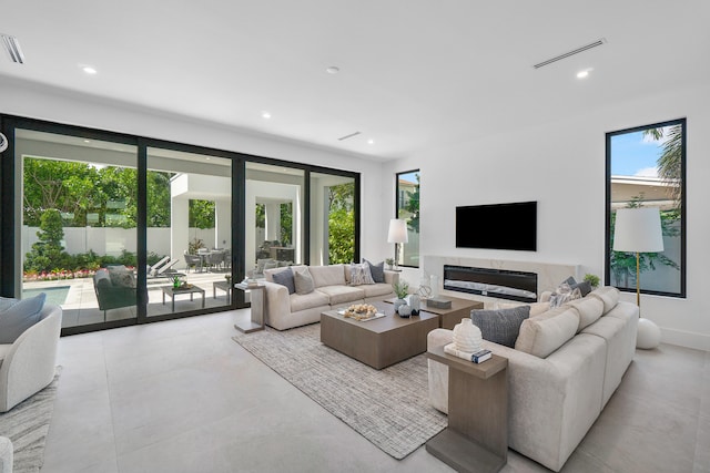 living room featuring a healthy amount of sunlight, a high end fireplace, and light tile floors