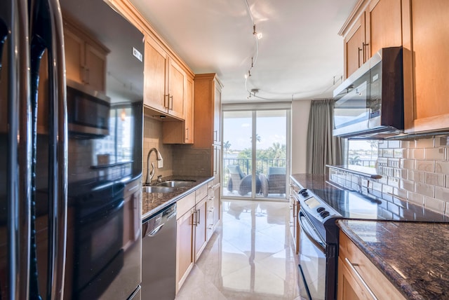 kitchen with sink, rail lighting, stainless steel appliances, tasteful backsplash, and dark stone counters