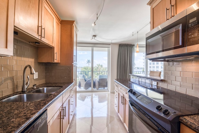 kitchen with sink, dark stone countertops, stainless steel appliances, and tasteful backsplash