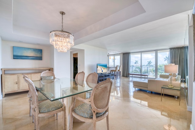 dining space with a raised ceiling and a notable chandelier