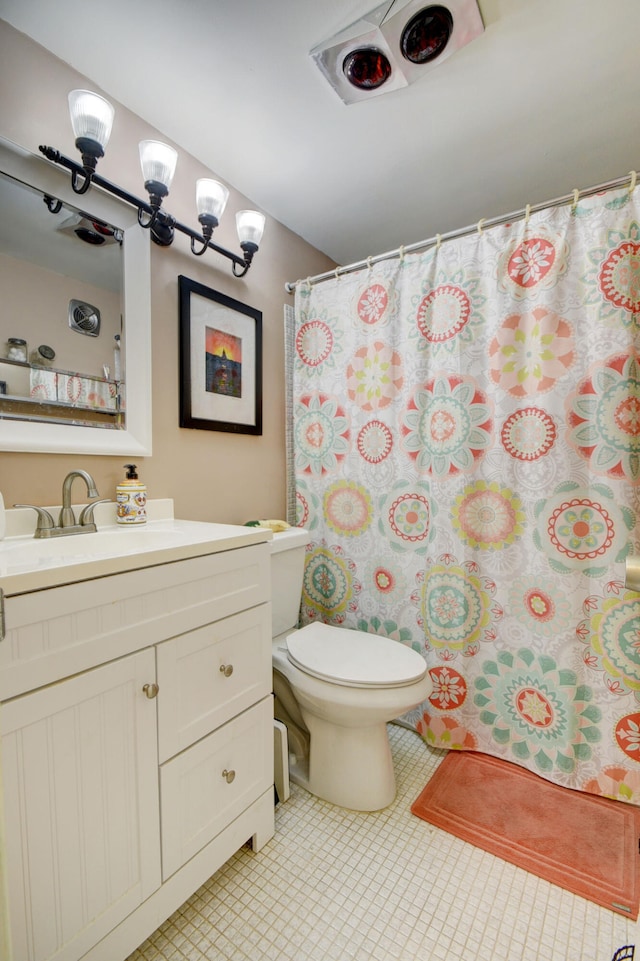 bathroom featuring tile flooring, vanity, and toilet