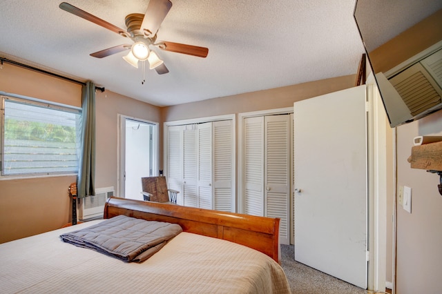 bedroom featuring multiple closets, carpet, ceiling fan, and a textured ceiling