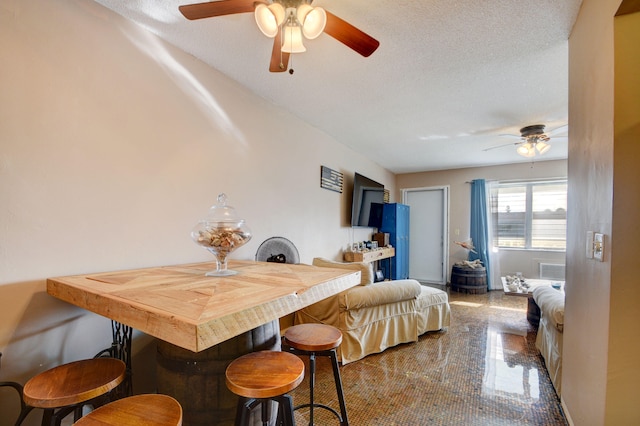 dining space featuring ceiling fan and a textured ceiling