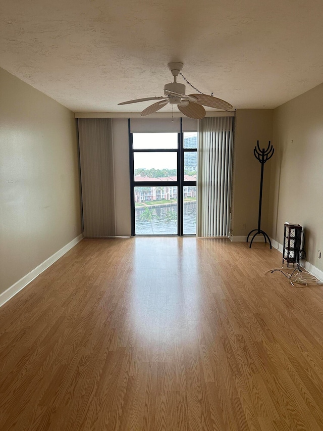 spare room featuring floor to ceiling windows, wood-type flooring, and ceiling fan