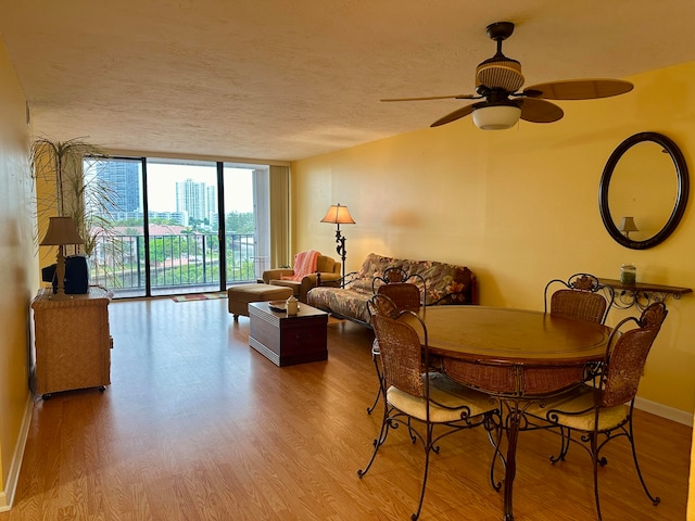 dining area featuring a textured ceiling, ceiling fan, floor to ceiling windows, and wood-type flooring