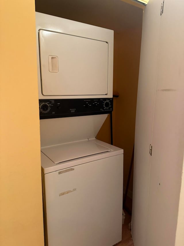 laundry area with hardwood / wood-style flooring and stacked washer and dryer