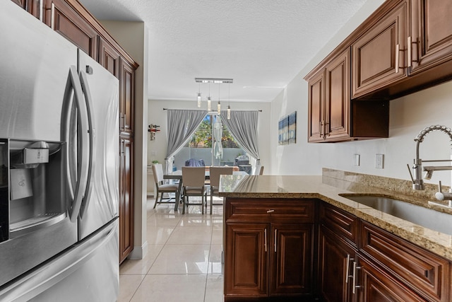 kitchen with light tile patterned floors, a textured ceiling, a sink, stainless steel refrigerator with ice dispenser, and light stone countertops