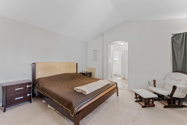 bedroom featuring arched walkways, vaulted ceiling, and light colored carpet