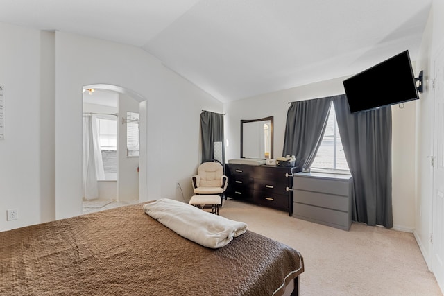 bedroom featuring arched walkways, lofted ceiling, and light colored carpet