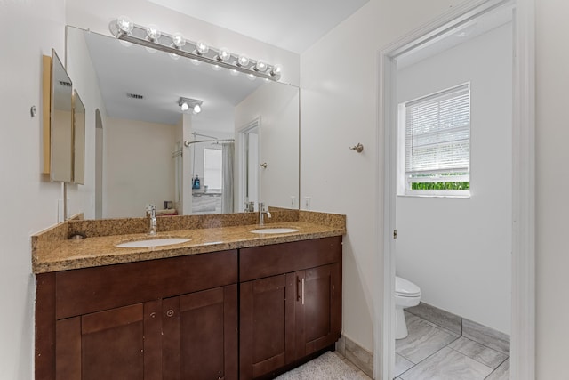 full bathroom with toilet, a shower stall, double vanity, and a sink