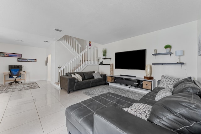 living area with stairs, visible vents, a textured ceiling, and light tile patterned flooring