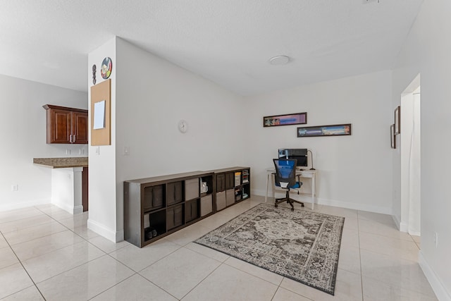 home office featuring light tile patterned floors, baseboards, and a textured ceiling