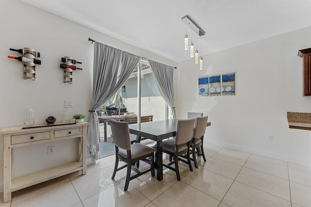 dining space with light tile patterned flooring, a textured ceiling, and baseboards