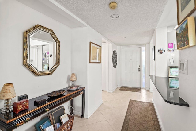 corridor with a textured ceiling and light tile flooring