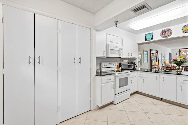 kitchen featuring white cabinets, sink, white appliances, and light tile floors