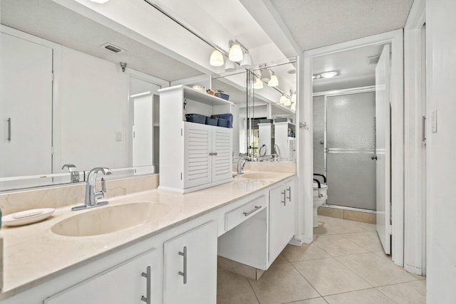 bathroom featuring tile flooring, a textured ceiling, double sink, vanity with extensive cabinet space, and toilet