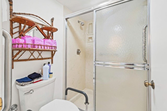 bathroom featuring a shower with door and toilet