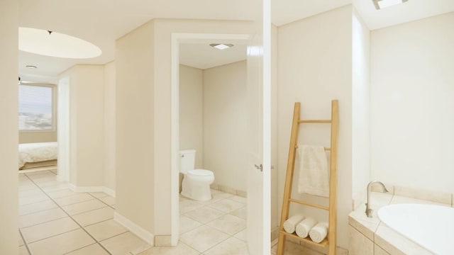 bathroom featuring tile patterned floors, tiled tub, and toilet