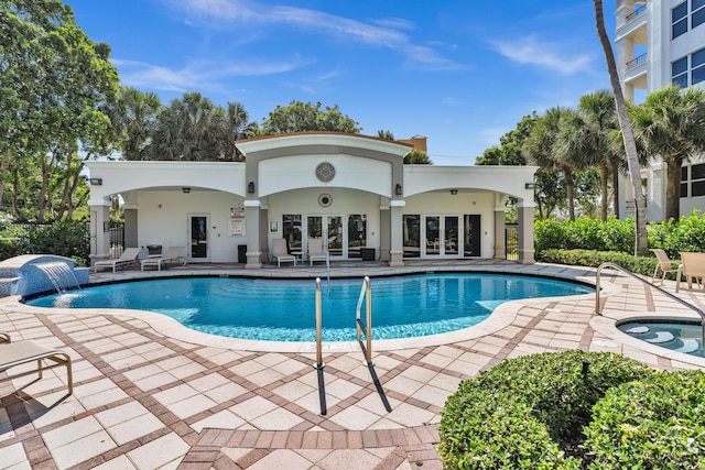 view of swimming pool featuring pool water feature, an in ground hot tub, a patio, and french doors