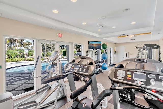 exercise room with french doors, a raised ceiling, and ceiling fan