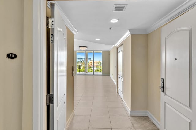 corridor featuring light tile patterned floors, vaulted ceiling, and ornamental molding