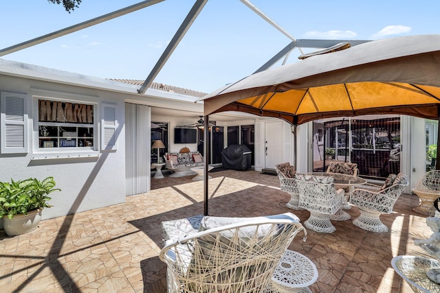 view of patio / terrace featuring a gazebo, grilling area, ceiling fan, and glass enclosure