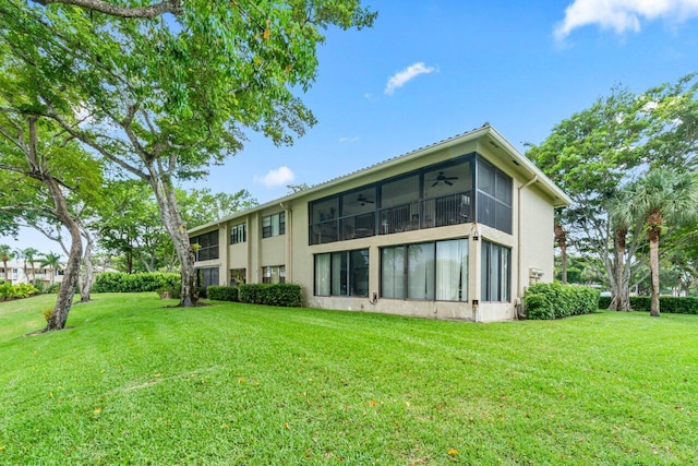 rear view of house featuring a lawn and ceiling fan