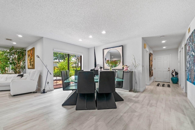 dining room with a textured ceiling and light hardwood / wood-style flooring