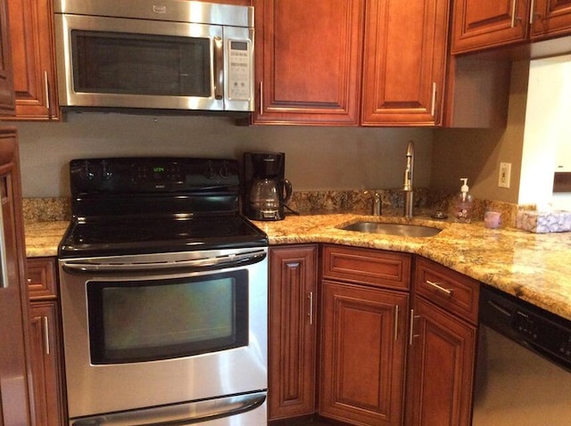 kitchen with appliances with stainless steel finishes, sink, and light stone counters