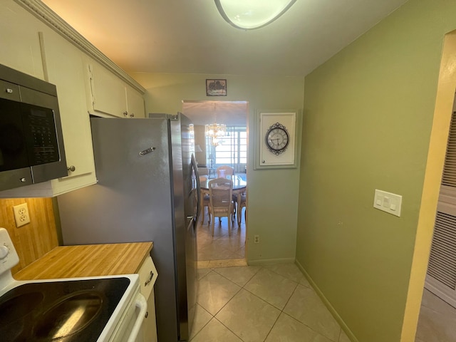 kitchen featuring white range, white cabinets, an inviting chandelier, and light tile flooring