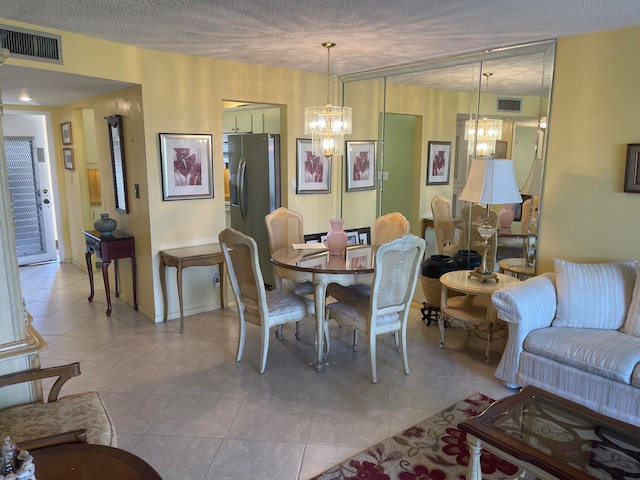 tiled dining area featuring a notable chandelier and a textured ceiling