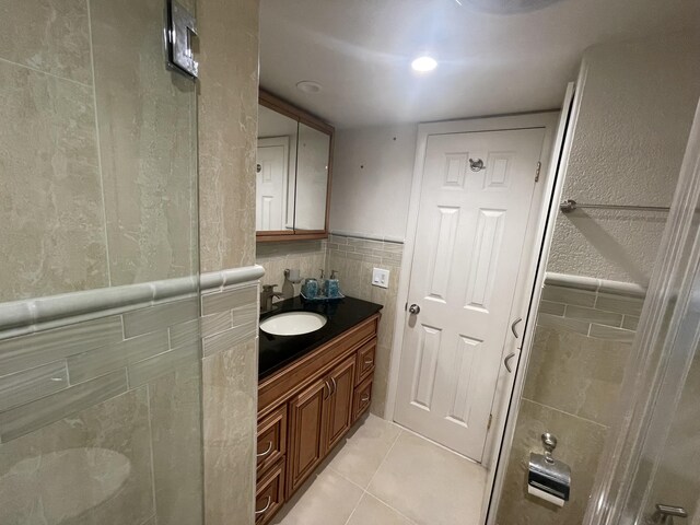 bathroom with backsplash, tile flooring, vanity, and tile walls