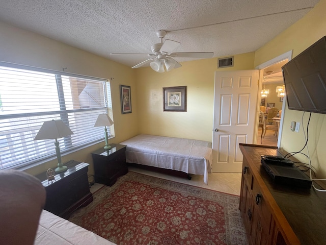 tiled bedroom with ceiling fan and a textured ceiling