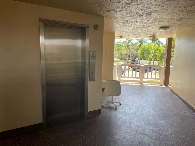 hallway featuring a textured ceiling and elevator