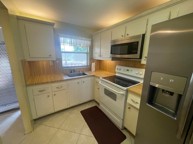 kitchen featuring white cabinetry, appliances with stainless steel finishes, sink, and light tile floors