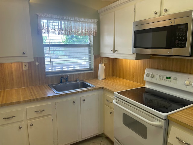 kitchen featuring white electric stove, a healthy amount of sunlight, white cabinetry, and light tile floors