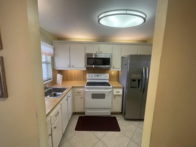 kitchen featuring sink, white cabinets, light tile flooring, and stainless steel appliances