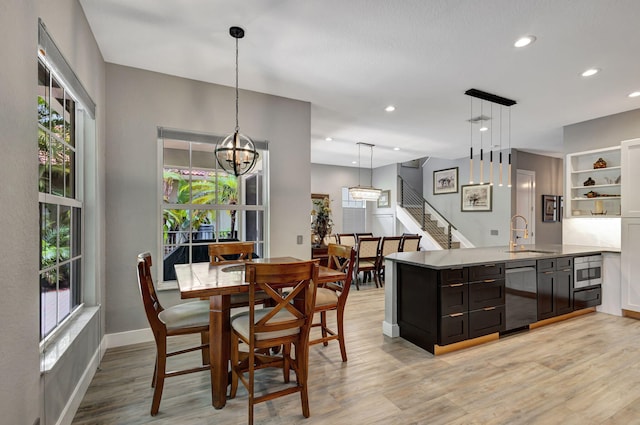 dining area with a chandelier, sink, and light hardwood / wood-style flooring