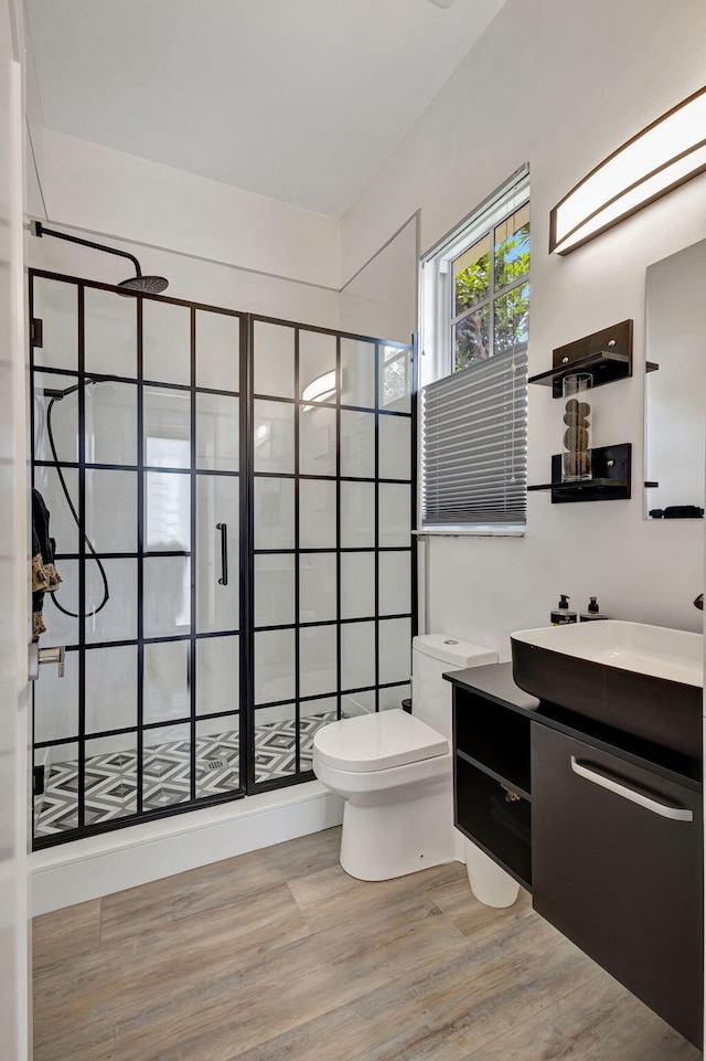 bathroom featuring toilet, vanity, hardwood / wood-style floors, and walk in shower