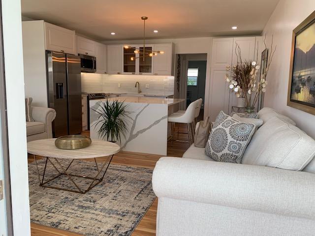 living room featuring a notable chandelier, sink, and light hardwood / wood-style flooring