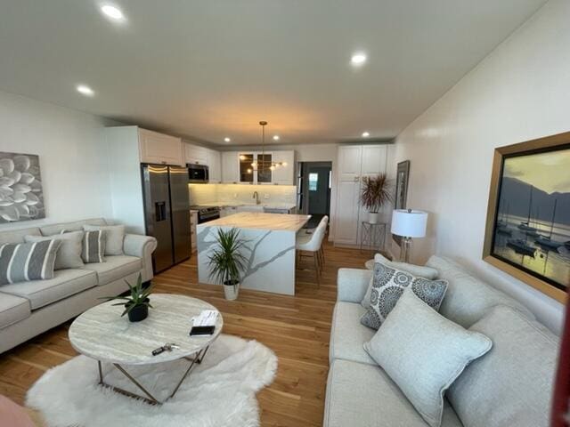 living room with light wood-type flooring and a chandelier