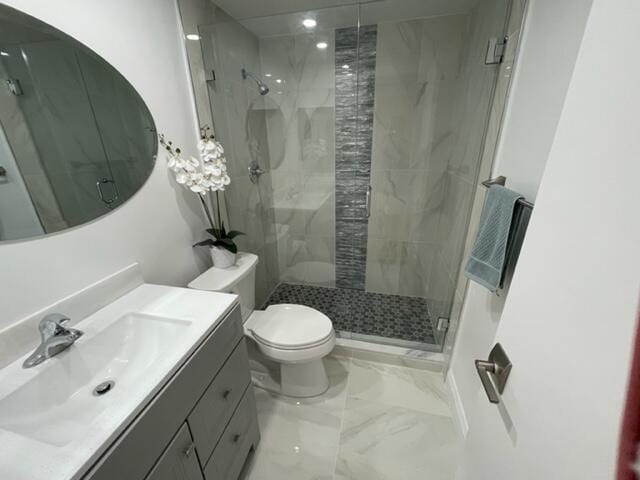 bathroom featuring vanity, toilet, and a shower with door