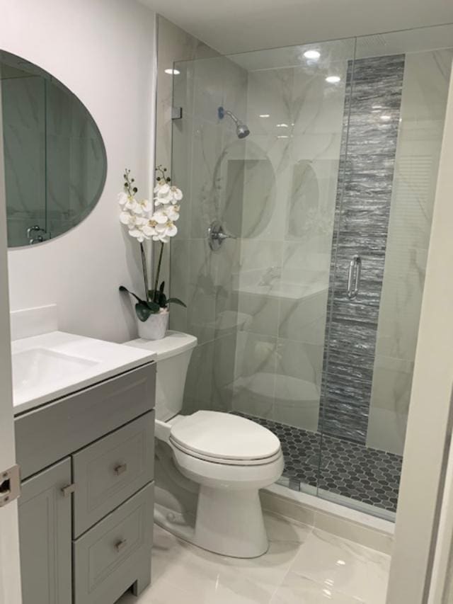 bathroom featuring vanity, toilet, and a shower with shower door